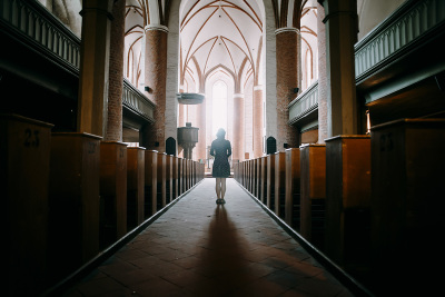 Woman standing in the aisle of a church.