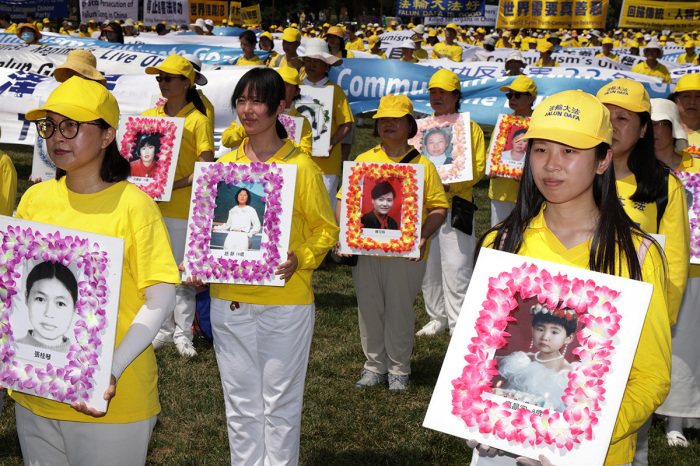 Falun Gong practitioners and supporters hold pictures of victims who were persecuted by the Chinese government as they take part in an annual rally and demonstration at the National Mall on July 16, 2021, in Washington, D.C. Members of Falun Gong held the event against the Chinese government’s persecution of the group and its practitioners. 
