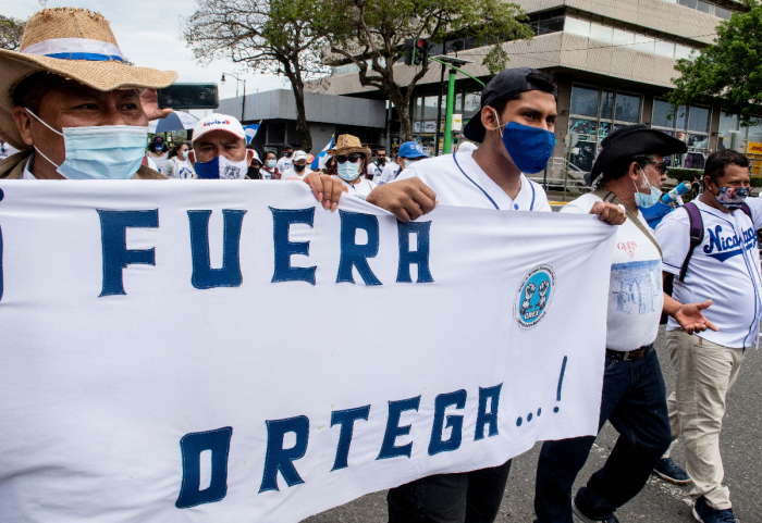 Nicaraguans living in Costa Rica carry a banner reading “Ortega Out” as they demonstrate in San Jose to commemorate the third anniversary of the beginning of the protests against the government of Nicaraguan President Daniel Ortega on April 18, 2021. Nicaragua’s political crisis erupted in April 2018, when protests mushroomed into a popular uprising that was met with a brutal crackdown in which hundreds were killed. 
