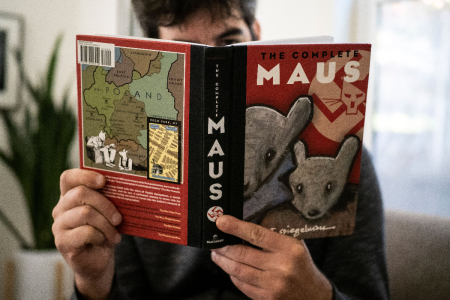This illustration photo taken in Los Angeles, California on January 27, 2022, shows a person holding the graphic novel "Maus" by Art Spiegelman.