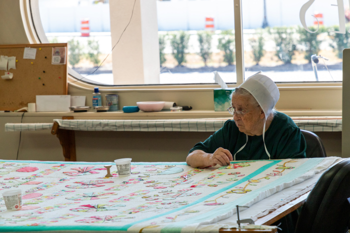 An Amish woman quilts inside Alma Sue’s Quilt Shop in Sarasota, Florida. (photo by Dennis Lennox)