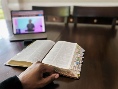 A woman watches online church service on a digital tablet.