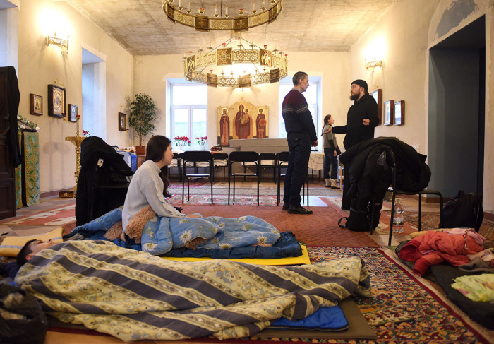 Ukrainian priest Iov Olchansky, 33, talks with displaced Ukrainians at the Resurrection New Athos Monastery in the western Ukrainian city of Lviv on March 5, 2022. - 'The Russian president is the Cain of today,' said a Ukrainian priest, referring to the Old Testament figure who murdered Abel, his own brother. A member of the Russian Orthodox Church, he was calling for a break with the mother church in Moscow following Russia's invasion of his country. 
