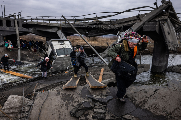 Evacuees cross a destroyed bridge as they flee the city of Irpin, northwest of Kyiv, on March 7, 2022. - Ukraine dismissed Moscow’s offer to set up humanitarian corridors from several bombarded cities on Monday after it emerged some routes would lead refugees into Russia or Belarus. The Russian proposal of safe passage from Kharkiv, Kyiv, Mariupol and Sumy had come after terrified Ukrainian civilians came under fire in previous ceasefire attempts. 