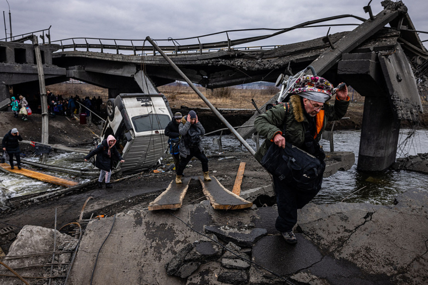 Evacuees cross a destroyed bridge as they flee the city of Irpin, northwest of Kyiv, on March 7, 2022. - Ukraine dismissed Moscow’s offer to set up humanitarian corridors from several bombarded cities on Monday after it emerged some routes would lead refugees into Russia or Belarus. The Russian proposal of safe passage from Kharkiv, Kyiv, Mariupol and Sumy had come after terrified Ukrainian civilians came under fire in previous ceasefire attempts.