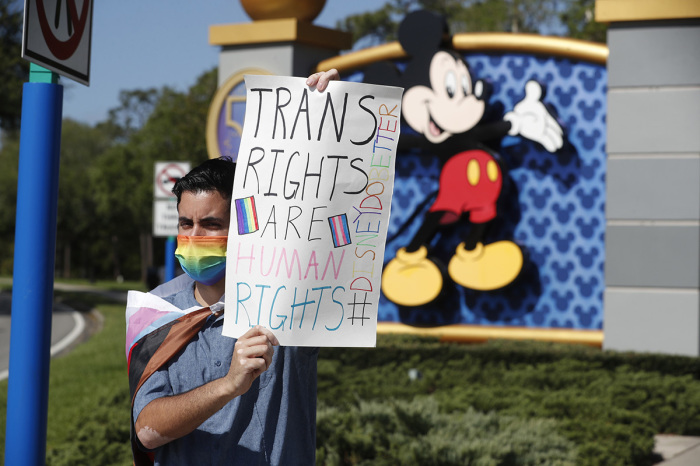 Disney employee Nicholas Maldonado holds a sign while protesting outside of Walt Disney World on March 22, 2022, in Orlando, Florida.
