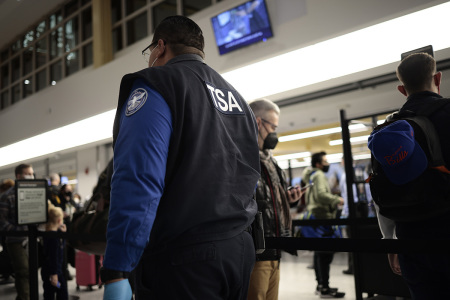 TSA Officer watches people go through the security checkpoint at the Ronald Reagan Washington National Airport on November 24, 2021 in Arlington, Virginia. FAA expects the number of travelers for Thanksgiving to reach pre-pandemic levels, with more than 53 million people traveling around the holiday.