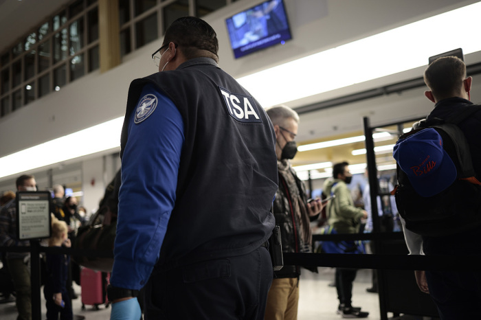 TSA Officer watches people go through the security checkpoint at the Ronald Reagan Washington National Airport on November 24, 2021 in Arlington, Virginia. FAA expects the number of travelers for Thanksgiving to reach pre-pandemic levels, with more than 53 million people traveling around the holiday. 