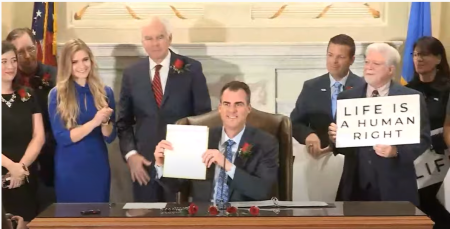 Oklahoma Gov. Kevin Stitt poses for a picture with Senate Bill 612, a pro-life bill he just signed into law that would ban nearly all abortions in the state except those performed to "save the life of a pregnant woman in a medical emergency," April 12, 2022.