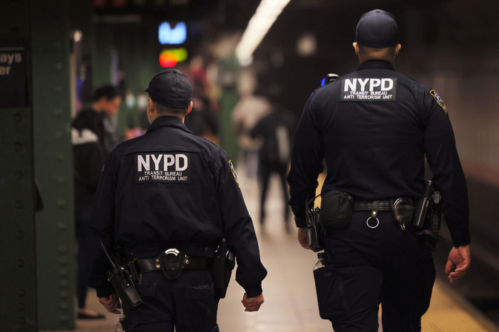 NYPD officers patrol the subway platform at the Atlantic Avenue subway station on April 13, 2022, in the Sunset Park neighborhood of Brooklyn in New York City. A manhunt is underway for a gunman who shot 10 people, critically injuring five on the N train during Tuesday's morning rush hour. The suspect, wearing a gas mask, tossed smoke grenades on the floor and fired 33 shots before leaving the scene. At least 13 other commuters suffered injuries due to smoke inhalation, falls, and panic attacks. The police on Tuesday evening named a 'person of interest' in the mass shooting and believe that they have found his personal belongings left on the train that includes a Glock 9-millimeter handgun and a key to a U-Haul van. Mayor Eric Adams this morning announced that Frank James, the 'person of interest' is now considered a suspect. 