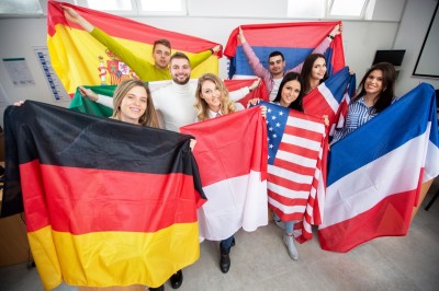 Students holding various flags of different countries in the classroom, student exchange.