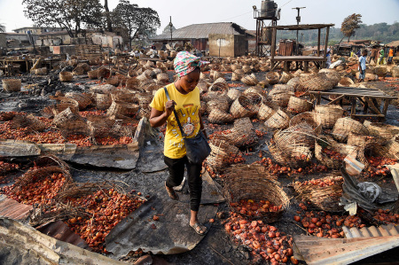 A lady walks among baskets full of tomatoes vandalized after deadly ethnic clashes between the northern Fulani and southern Yoruba traders at Shasha Market in Ibadan, southwest Nigeria, on February 15, 2021.