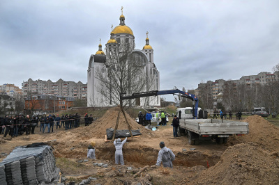 Journalists gather as bodies are exhumed from a mass-grave in the grounds of the St. Andrew and Pyervozvannoho All Saints church in the Ukrainian town of Bucha, northwest of Kyiv on April 13, 2022. - The European Commission President visited the mass grave in Bucha on April 8, where Russian forces are accused by Ukraine's allies of carrying out atrocities against civilians.