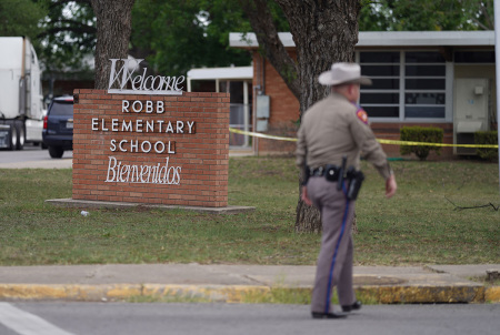 An officer walks outside of Robb Elementary School in Uvalde, Texas, on May 24, 2022. - An 18-year-old gunman killed 18 children and two teachers at an elementary school in Texas on Tuesday, according to the state's governor, in the nation's deadliest school shooting in years.