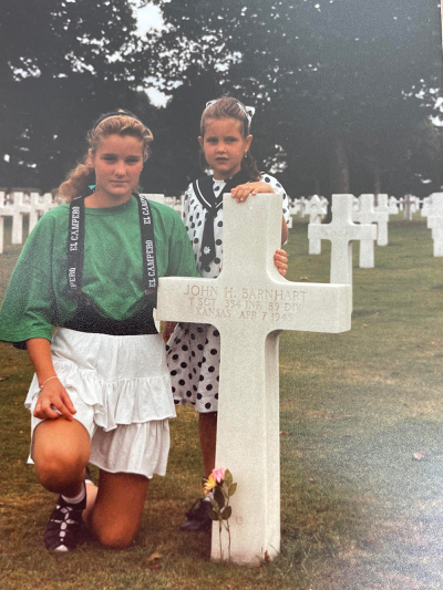Sisters Claudia Welzen-Holsgens and Lucinda Van de Kuit-Holsgens in their youth at the grave of T Sgt. John H. Barnhart. 