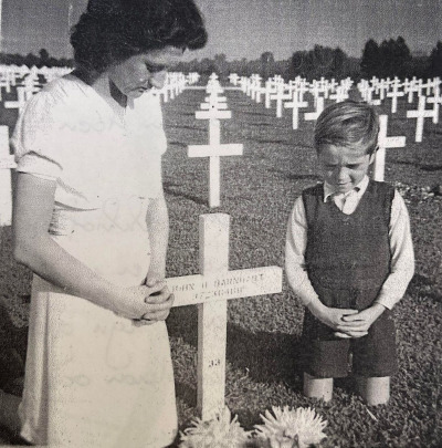 Dutch citizens pray beside a wooden cross laid for the soldier they adopted at the Netherlands American Cemetery in Margraten before the final headstones were placed at each grave. 