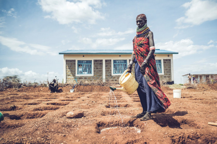 A Kenyan woman pours water into the dirt in Turkana County, Kenya. 