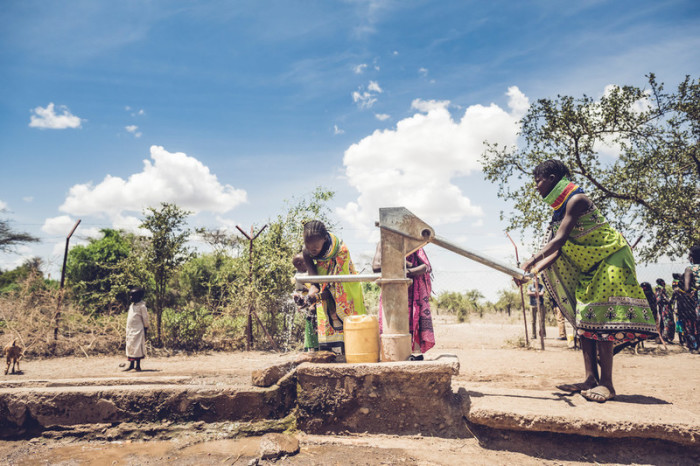 Two women in Kenya stand at a pump to obtain water in Turkana County, Kenya. 