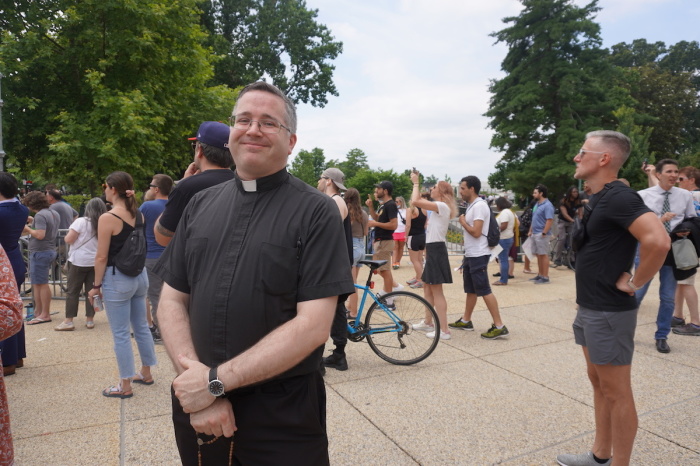 Fr. Tim Wezner stands in front of the Supreme Court of the United States in Washington D.C. to pray with a rosary bead necklace, amid hundreds of pro-lifers and pro-choicers rallying after Dobbs v. Jackson Women's Health Organization was announced, June 24, 2022. 