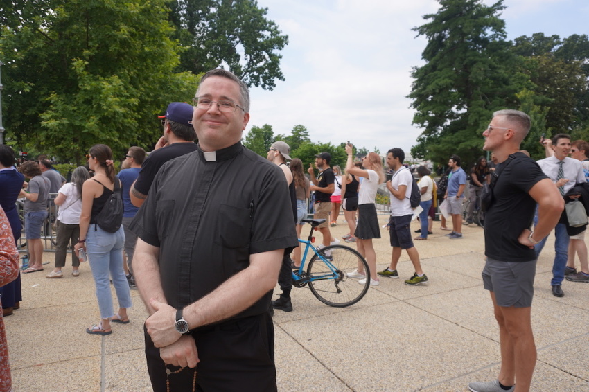 Fr. Tim Wezner stands in front of the Supreme Court of the United States in Washington D.C. to pray with a rosary bead necklace, amid hundreds of pro-lifers and pro-choicers rallying after Dobbs v. Jackson Women's Health Organization was announced, June 24, 2022.