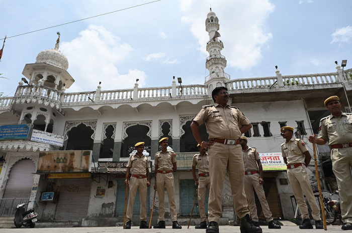 Policemen stand guard during a curfew imposed by authorities following the killing of Hindu tailor Kanhaiya Lal, who was allegedly killed by two Muslim men for supporting a former spokeswoman of the ruling Bharatiya Janata Party (BJP) for her remarks about the Islamic prophet Muhammad, in Udaipur on July 1, 2022. 