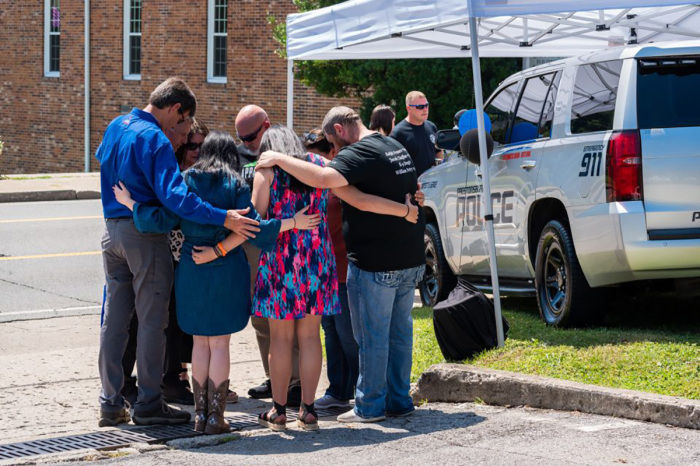Billy Graham Rapid Response Team members gather around for prayer near a memorial set up for those who lost their lives in the shooting.