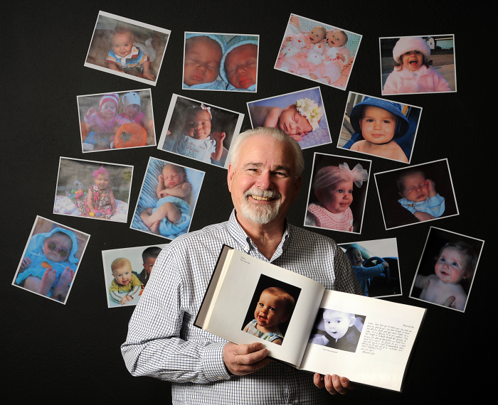 Nightlight Christian Adoption President Emeritus Ronald L. Stoddart, an adoption attorney who started the Snowflakes program, poses with photos of babies.