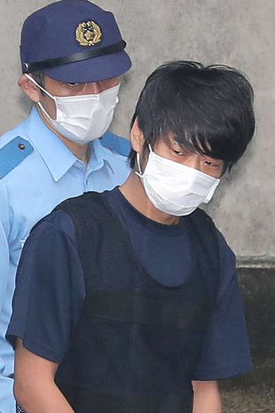 Tetsuya Yamagami (R), the man accused of murdering former Japanese Prime Minister Shinzo Abe, is escorted by police while leaving the Nara Nishi police station to head to the prosecutor's office in Nara on July 10, 2022. 