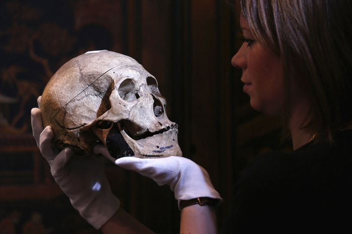 A gallery assistant at Bonhams auction house holds an engraved human skull on January 24, 2013, in London, England.