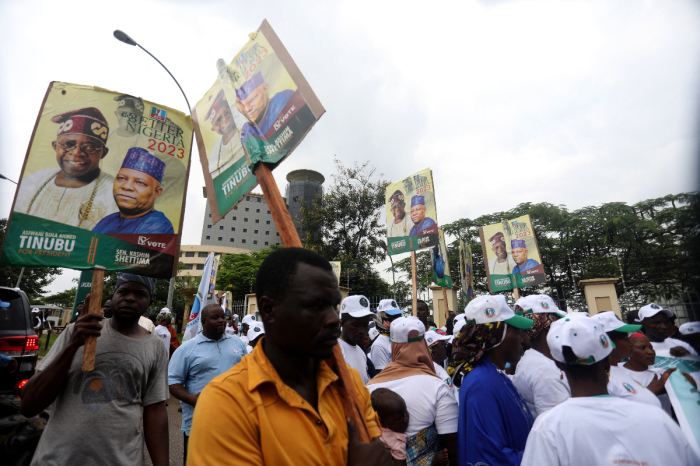 Supporters of Nigeria's All Progressive Congress (APC) ruling party hold posters of APC presidential and vice-presidential candidates outside a party meeting in Abuja on July 20, 2022. 