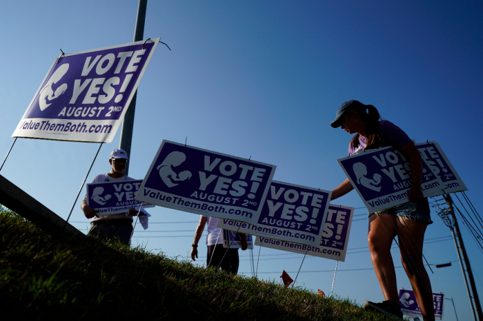 Supporters remove signs along 135th Street on August 01, 2022, in Olathe, Kansas. On August 2, voters will vote on whether or not to remove protection for abortion from the state constitution. 