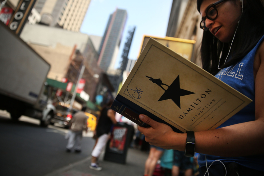 A woman displays her Hamilton autograph book outside the popular Broadway show "Hamilton" on June 21, 2016, in New York City.