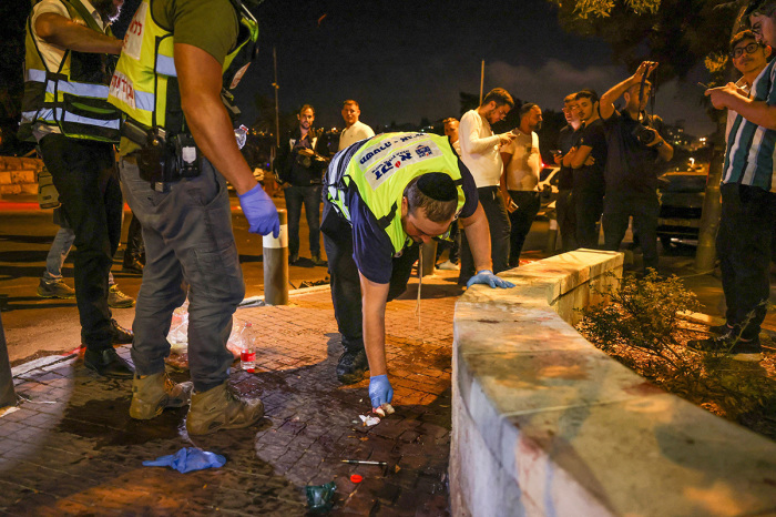 Zaka volunteers, an Ultra-Orthodox Jewish emergency response team, clean up blood stains after an attack outside Jerusalem's Old City, August 14, 2022. - Israeli police said they had arrested a suspect in a pre-dawn gun attack on a bus in central Jerusalem that wounded eight people according to an updated casualty toll. 