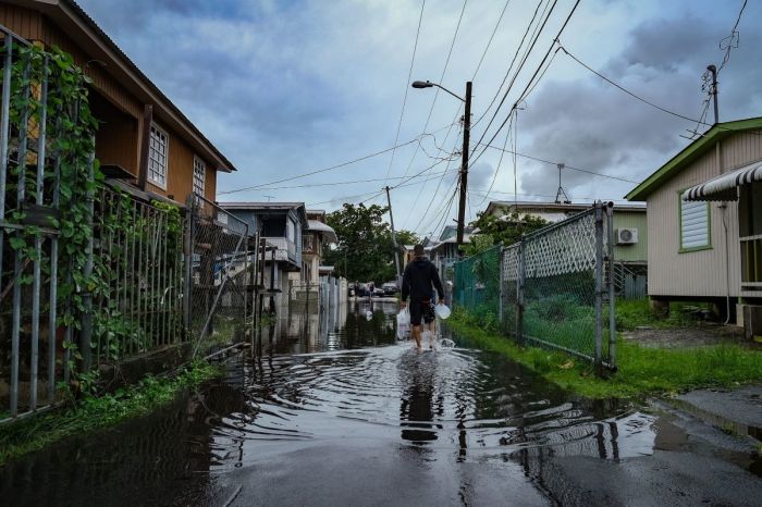 A man walks down a flooded street in the Juana Matos neighborhood of Catano, Puerto Rico, on Sept. 19, 2022, after the passage of Hurricane Fiona. 