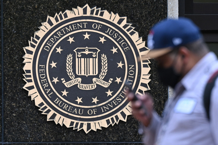A pedestrian walks past a seal reading 'Department of Justice Federal Bureau of Investigation,' displayed on the J. Edgar Hoover FBI building, in Washington, D.C., on Aug. 15, 2022. 