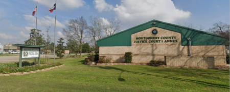 Flags fly outside of the headquarters for Montgomery County Justice of the Peace Precinct 1 in Willis, Texas.