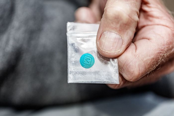 A person holds a plastic bag containing a fentanyl opiate.