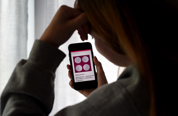 In this photo illustration, a person looks at an Abortion Pill (RU-486) for unintended pregnancy from Mifepristone displayed on a smartphone on May 8, 2020, in Arlington, Virginia. 