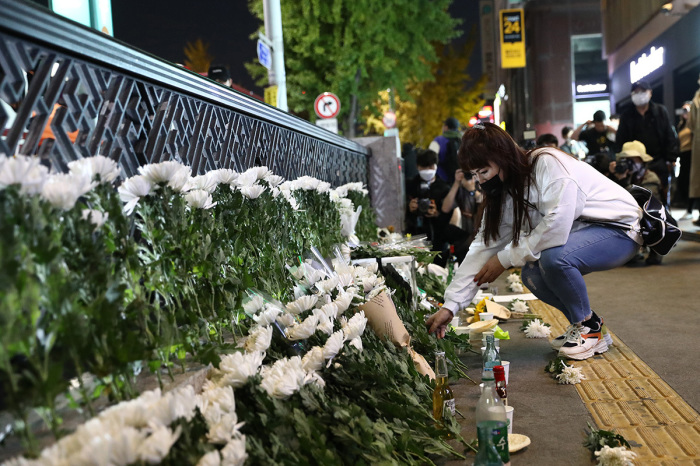 A woman lays flowers as she mourns at the street of a deadly stampede during a Halloween festival on Oct. 30, 2022, in Seoul, South Korea. More than 150 people have been reported killed and at least 150 others were injured in a deadly stampede in Seoul's Itaewon district, after huge crowds of people gathered for Halloween parties, according to fire authorities. 