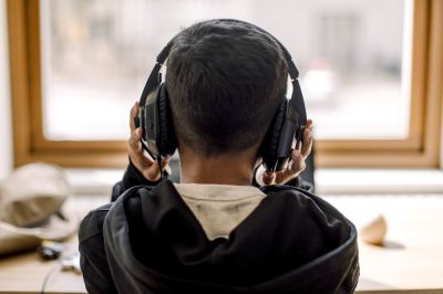 Rear view of autistic boy with headphones at home