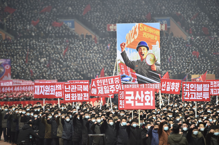 In this photo taken on January 5, 2023, people hold placards including one (top) that translates as 2023 - Key year of five-year plan implementation during a rally to vow to carry through the decisions of the 6th Plenary Meeting of the 8th Central Committee of the Workers' Party of Korea (WPK) at the Mayday Stadium in Pyongyang.