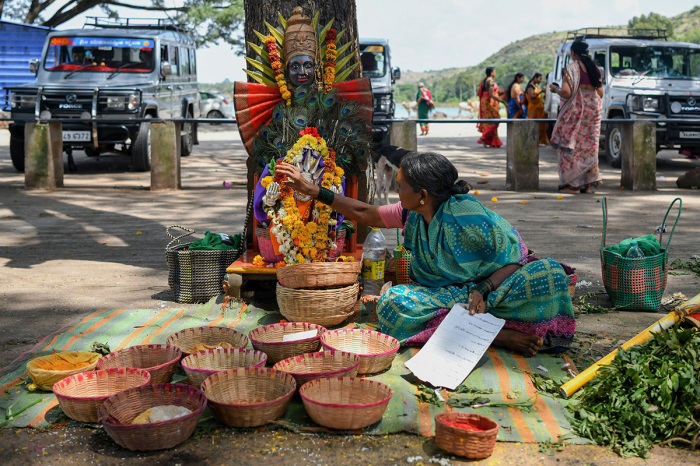 In this picture taken on September 21, 2022, a former 'devadasi' woman places a flower garland on a decorated mask of the Hindu Goddess Yellamma Devi near a pond where 'devadasis' women who were dedicated by their families to the Hindu Goddess Yellamma Devi, cleanse themselves before visiting Yellamma Devi temple in Savadatti of Belgaum district, in India's Karnataka state. - Devadasis are expected to live a life of religious devotion, forbidden from marrying other mortals, and forced at puberty to sacrifice their virginity to an older man, in return for money or gifts. 