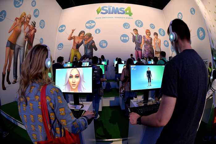 Visitors try out the game 'SIMS 4' at the Electronic Arts stand at the 2014 Gamescom gaming trade fair on August 14, 2014, in Cologne, Germany. 