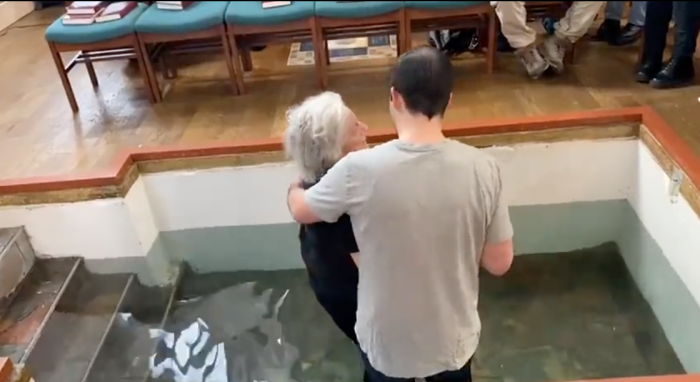 Regan Burton King, the lead pastor at The Angel Church in London, is seen baptizing a 77-year-old woman who has Parkinson’s disease.