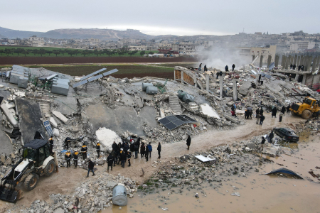 This aerial view shows residents, helped by bulldozers, searching for victims and survivors in the rubble of collapsed buildings following an earthquake in the town of Sarmada in the countryside of the northwestern Syrian Idlib province, early on February 6, 2023.