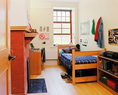 Dorm room with brick fireplace and wood floor.