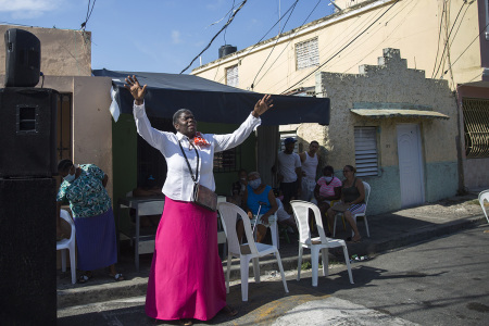 People pray as a woman from the Evangelical church preaches at the Maria Auxiliadora neighborhood in Santo Domingo, on April 10, 2020.