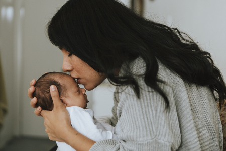 A mother holds an infant in her arms.