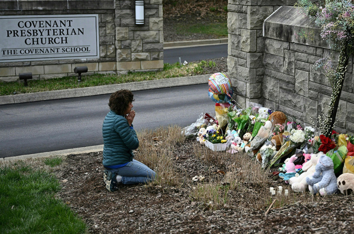 Robin Wolfenden prays at a makeshift memorial for victims outside the Covenant School building at the Covenant Presbyterian Church following a shooting, in Nashville, Tennessee, on March 28, 2023. - A heavily armed former trans-identified student killed three young children and three staff in what appeared to be a carefully planned attack at a private elementary school in Nashville on March 27, before being shot dead by police. Chief of Police John Drake named the suspect as Audrey Hale, 28, who the officer later said identified as transgender. 