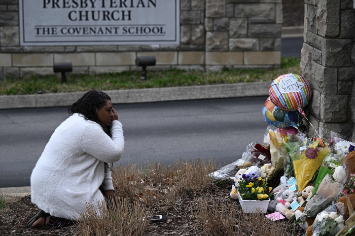 A woman pays her respects at a makeshift memorial for victims outside the Covenant School building at the Covenant Presbyterian Church following a shooting in Nashville, Tennessee, on March 28, 2023. A heavily armed trans-identified former student killed three young children and three staff in a carefully planned attack at a private elementary school in Nashville on March 27, before being shot dead by police. Chief of Police John Drake named the suspect as Audrey Hale, 28. 